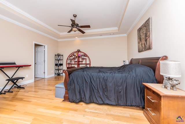 bedroom featuring a raised ceiling, light wood-type flooring, baseboards, and ornamental molding