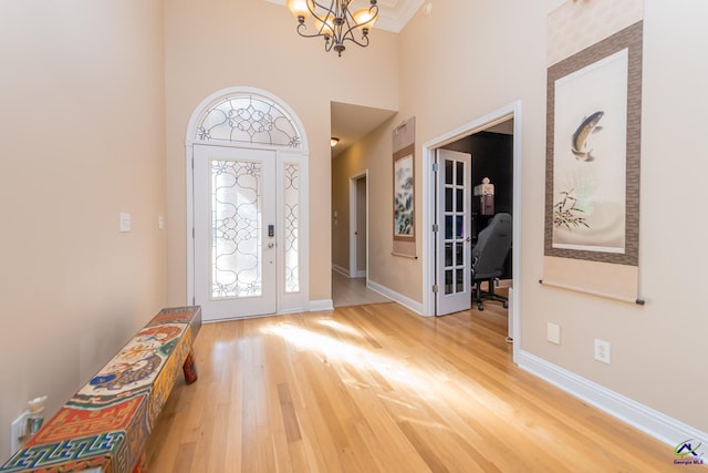 foyer featuring a healthy amount of sunlight, baseboards, an inviting chandelier, and wood finished floors