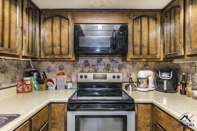 kitchen featuring tasteful backsplash, stainless steel range with electric stovetop, black microwave, and light countertops