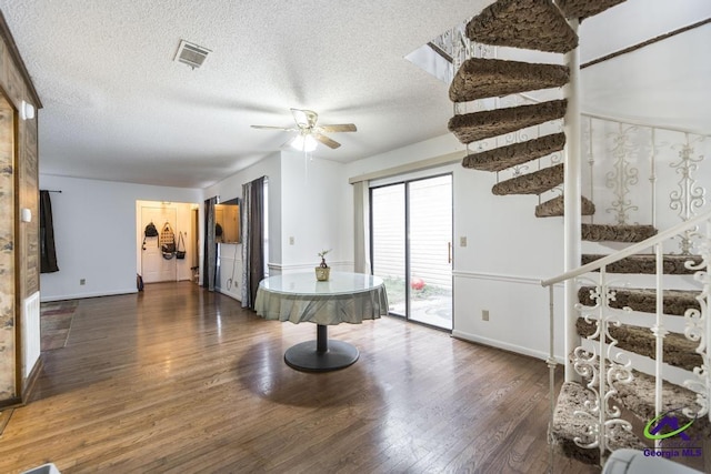 interior space with a ceiling fan, stairway, wood finished floors, and visible vents