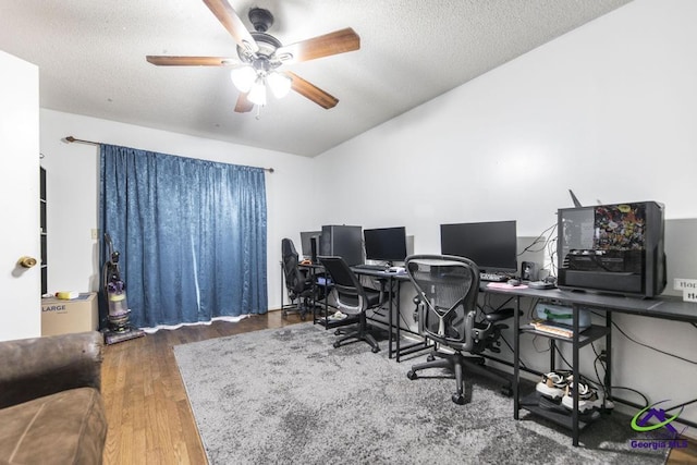 office space featuring a textured ceiling, lofted ceiling, wood finished floors, and ceiling fan