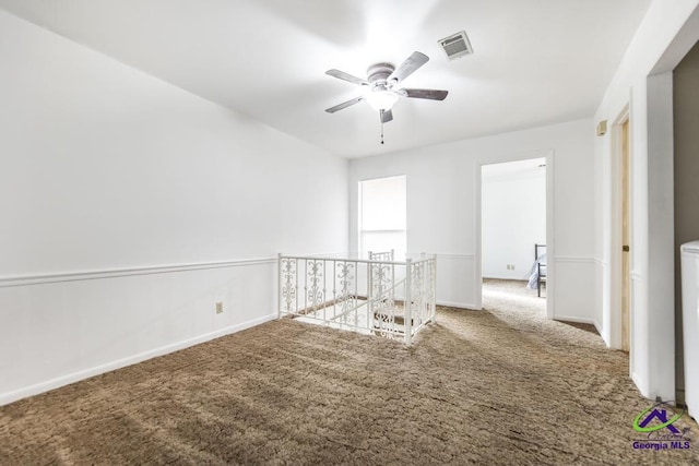 unfurnished room featuring visible vents, carpet flooring, baseboards, and a ceiling fan