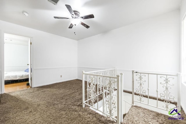 hallway with an upstairs landing, carpet flooring, and visible vents