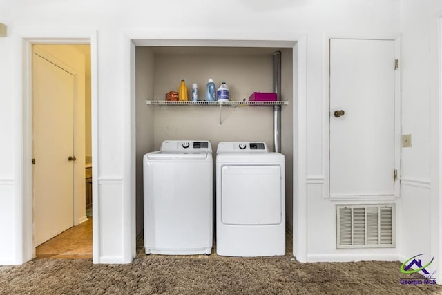 clothes washing area featuring visible vents, carpet floors, and washing machine and dryer