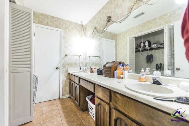 full bathroom with a closet, tile patterned floors, wallpapered walls, and a sink