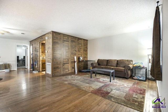 living area with a textured ceiling, a ceiling fan, and wood-type flooring