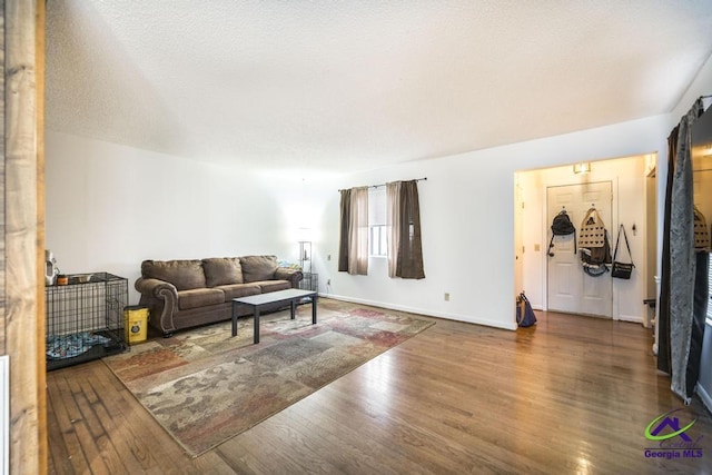 living area featuring a textured ceiling, baseboards, and wood finished floors