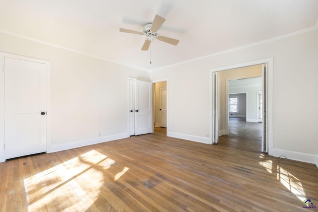 unfurnished bedroom featuring a ceiling fan, crown molding, baseboards, and hardwood / wood-style flooring