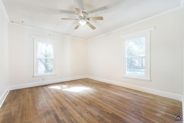 empty room with hardwood / wood-style flooring, crown molding, and baseboards