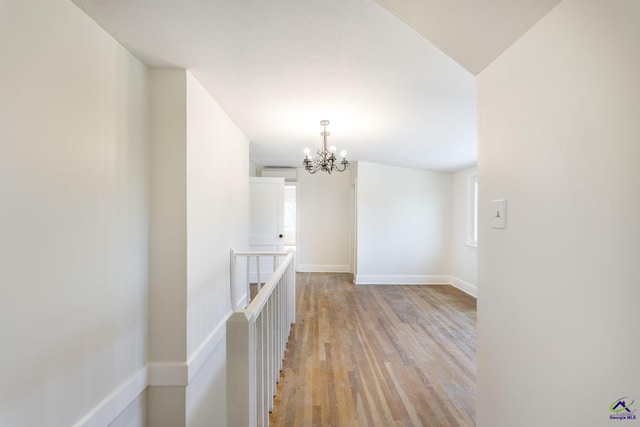 spare room featuring a healthy amount of sunlight, light wood-style floors, baseboards, and a chandelier