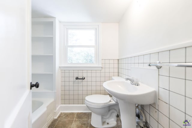 full bathroom with tile patterned flooring, a wainscoted wall, toilet, tile walls, and a shower