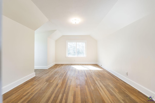 bonus room with baseboards, lofted ceiling, and hardwood / wood-style floors