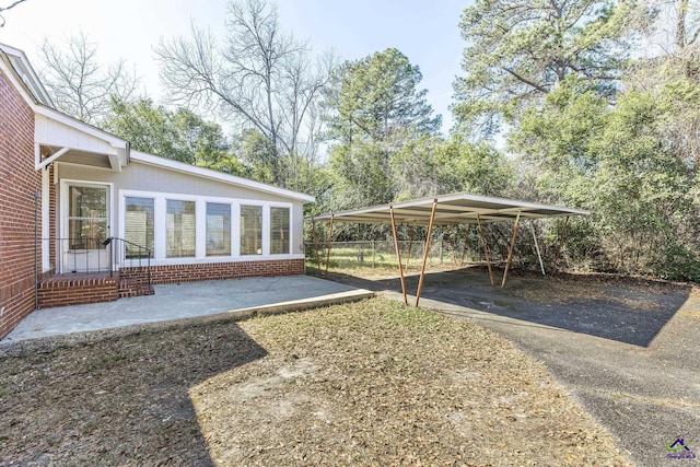 view of yard with a carport, driveway, and fence