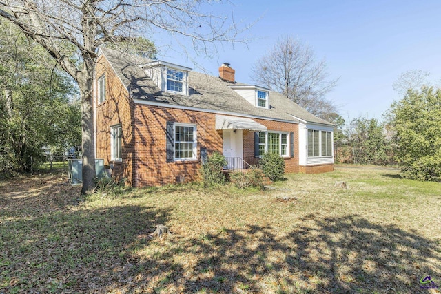 cape cod house with brick siding, a chimney, and a front lawn