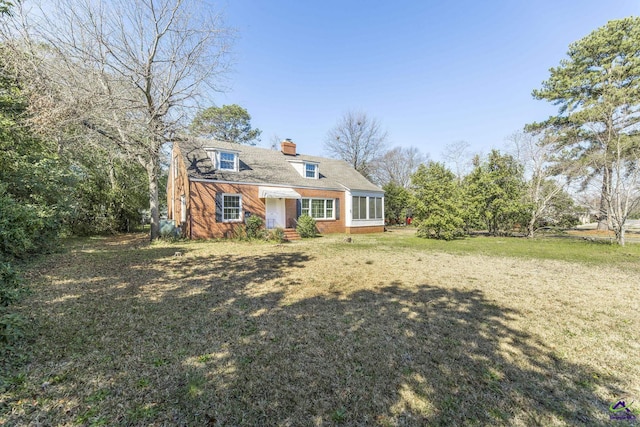 view of front of house with brick siding, a chimney, a front yard, and entry steps