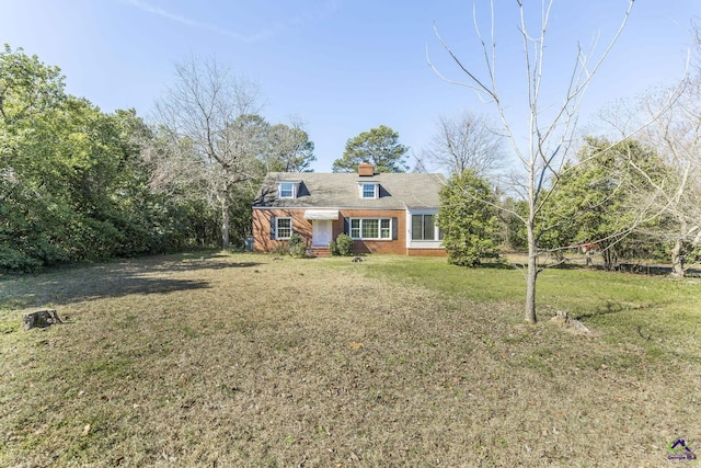 view of front of house featuring brick siding, a chimney, and a front lawn