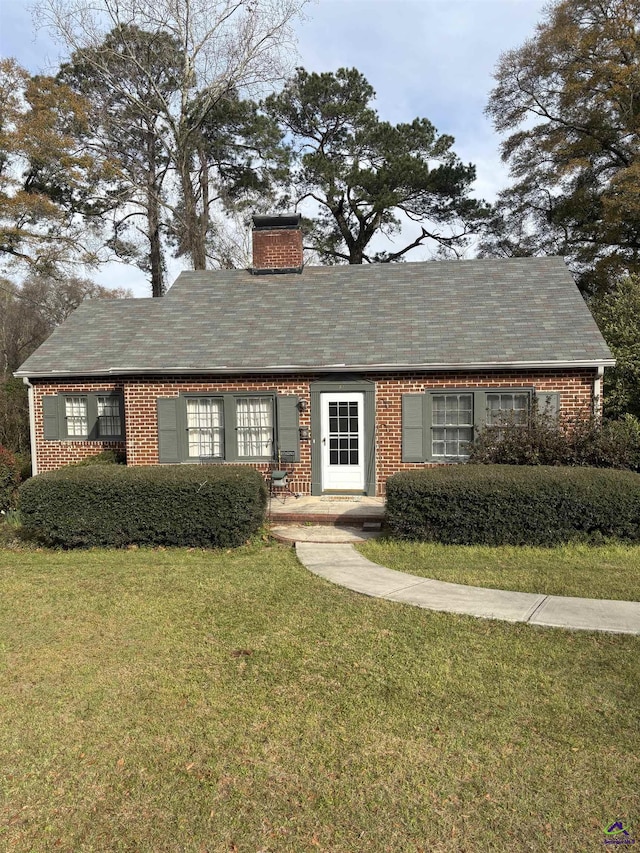 view of front facade with a chimney and a front lawn