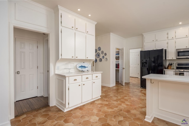 kitchen featuring white cabinets, appliances with stainless steel finishes, light countertops, and ornamental molding