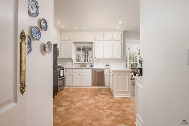 kitchen with a sink, stainless steel appliances, light countertops, white cabinetry, and tasteful backsplash