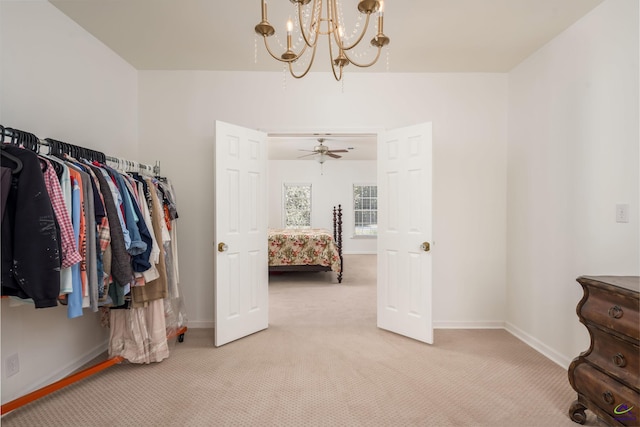 walk in closet with light colored carpet and an inviting chandelier