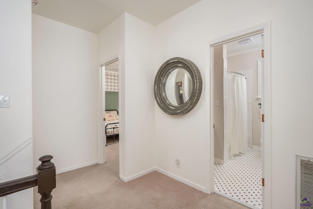 hallway featuring light colored carpet, visible vents, and baseboards