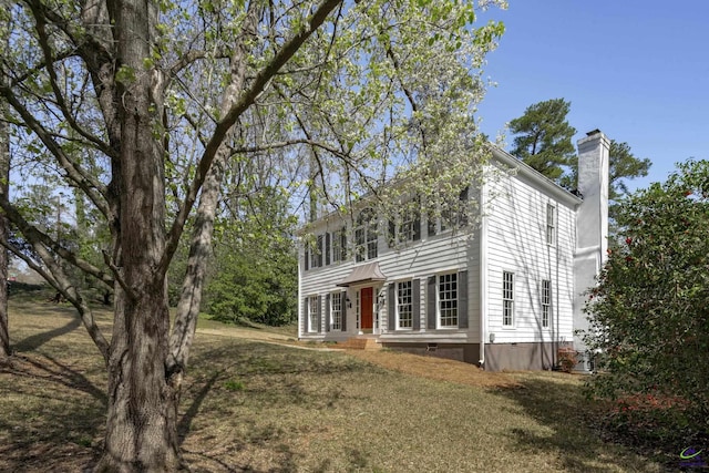 colonial inspired home with crawl space, a chimney, and a front lawn