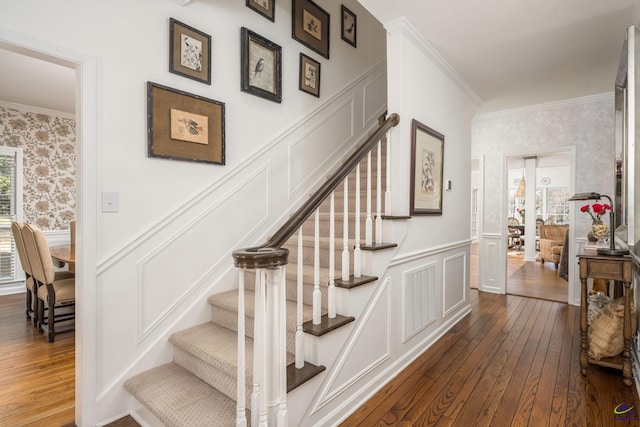 stairway with visible vents, wallpapered walls, crown molding, and a wainscoted wall