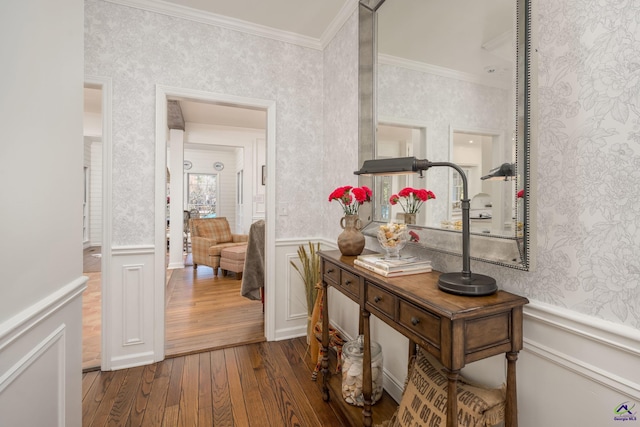 hall with a wainscoted wall, ornamental molding, and wallpapered walls