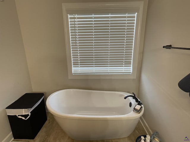 bathroom with a freestanding bath and baseboards