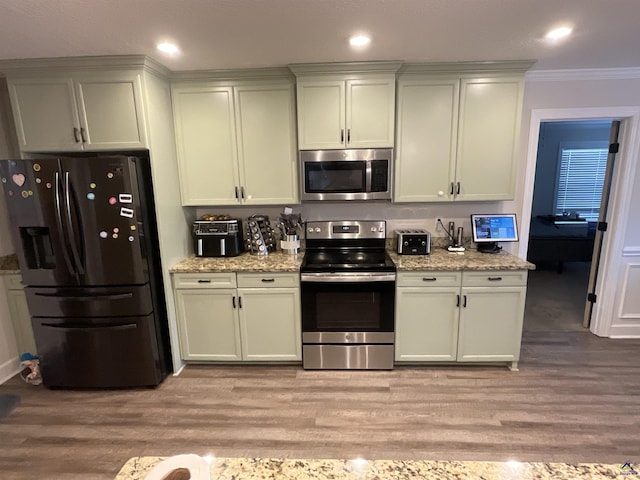 kitchen with light wood-type flooring, stainless steel appliances, light stone countertops, and ornamental molding