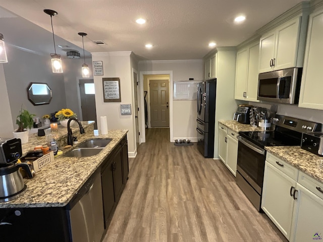 kitchen featuring light stone counters, visible vents, light wood finished floors, a sink, and appliances with stainless steel finishes