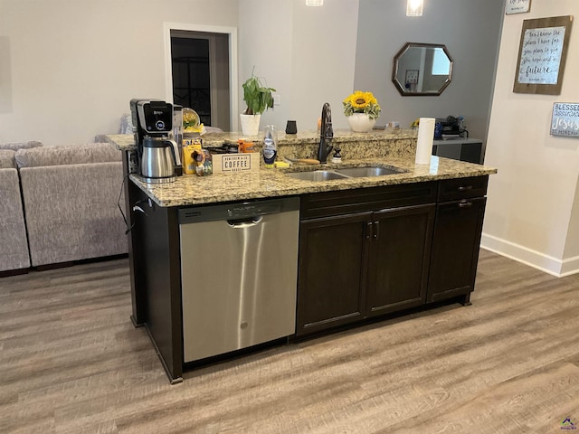 kitchen featuring stainless steel dishwasher, open floor plan, light wood-type flooring, and a sink