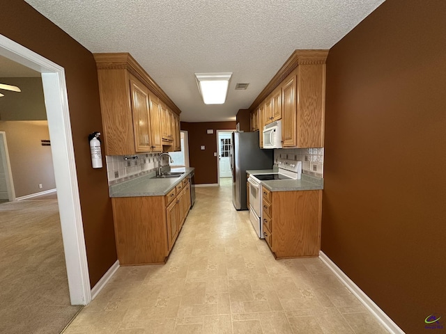 kitchen featuring a sink, visible vents, white appliances, and baseboards