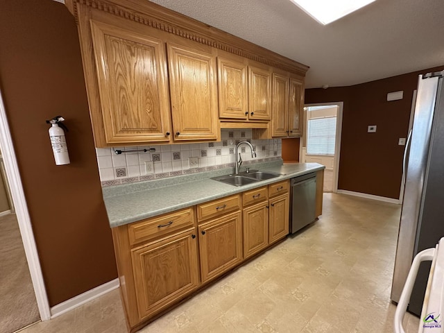 kitchen with backsplash, baseboards, light countertops, stainless steel appliances, and a sink