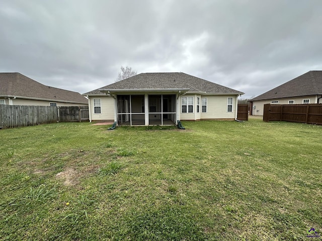 rear view of house with a yard, a fenced backyard, a sunroom, and a shingled roof