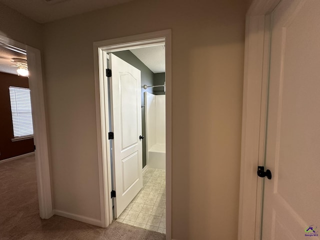 hall with light colored carpet and baseboards