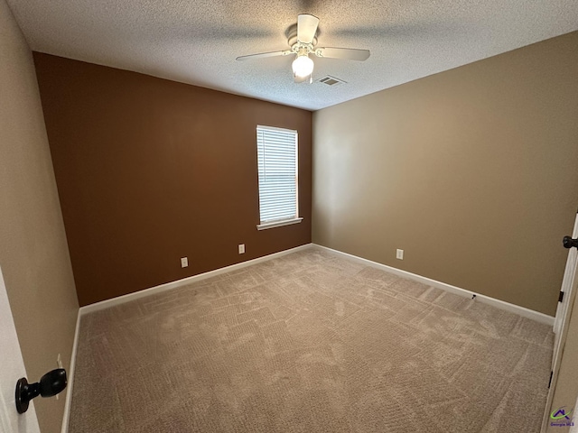 empty room with a textured ceiling, a ceiling fan, visible vents, and light carpet