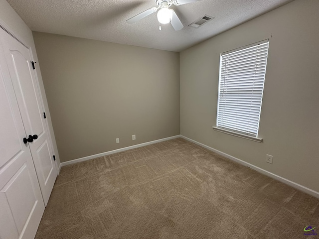 unfurnished room featuring a ceiling fan, visible vents, carpet floors, and a textured ceiling