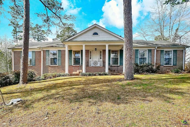 greek revival inspired property featuring brick siding, a porch, and a front lawn