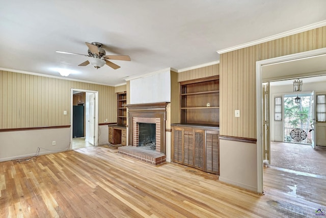 unfurnished living room featuring a fireplace, crown molding, wood finished floors, and ceiling fan