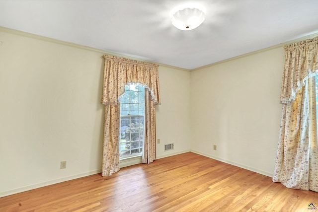 unfurnished room featuring visible vents, ornamental molding, baseboards, and wood finished floors