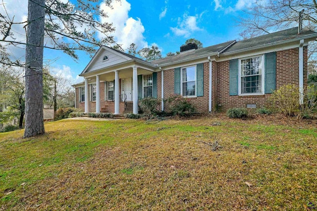 neoclassical home featuring brick siding, covered porch, a chimney, and a front yard