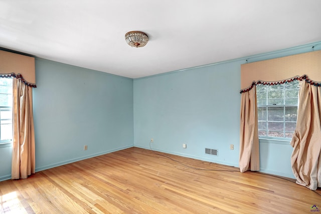 unfurnished room featuring wood finished floors, visible vents, and baseboards