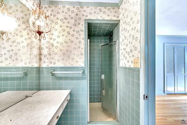 full bathroom featuring a wainscoted wall, a stall shower, and wallpapered walls