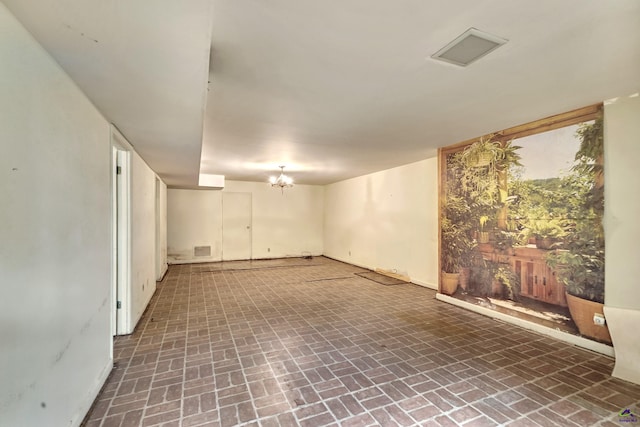 basement with brick floor, visible vents, and baseboards