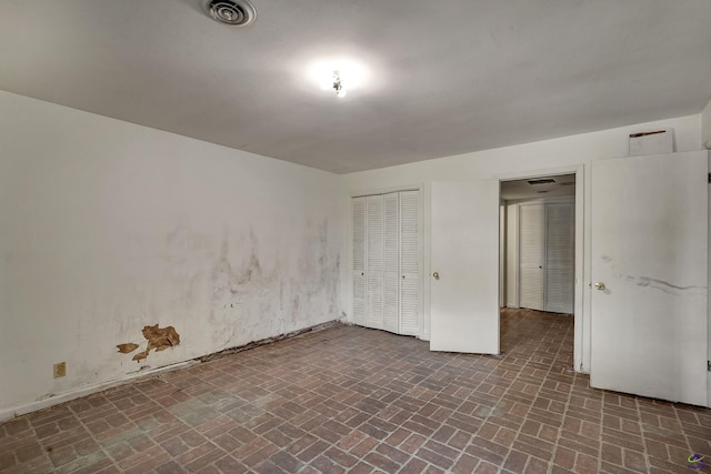 interior space featuring brick floor, visible vents, and a closet