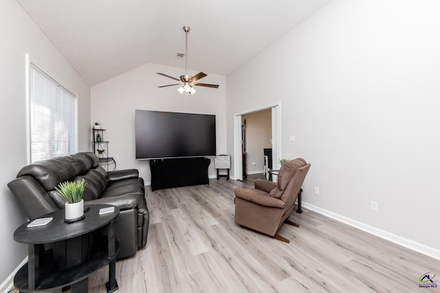 living area featuring baseboards, light wood-style floors, a ceiling fan, and vaulted ceiling