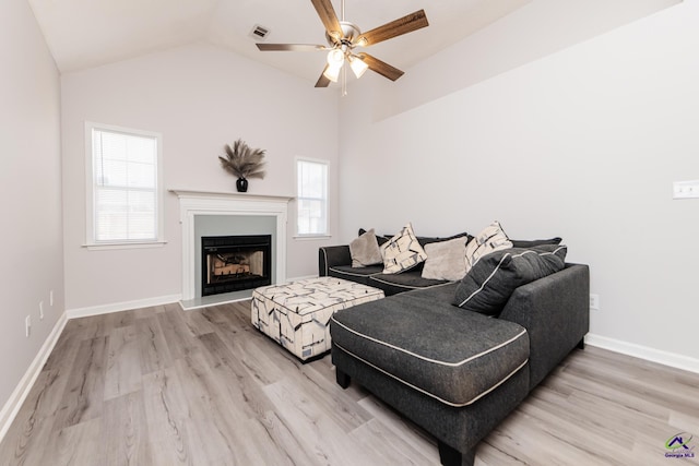 living area with visible vents, light wood-style floors, ceiling fan, and vaulted ceiling