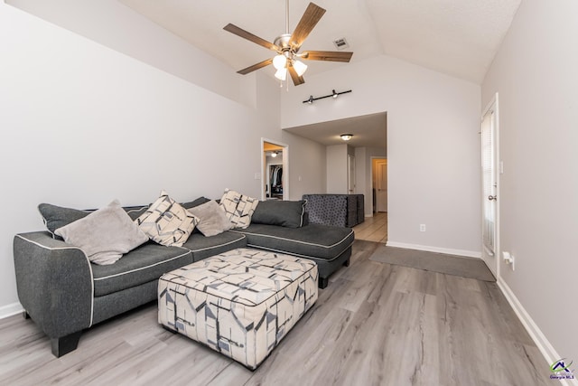 living area with visible vents, light wood-style flooring, baseboards, lofted ceiling, and ceiling fan