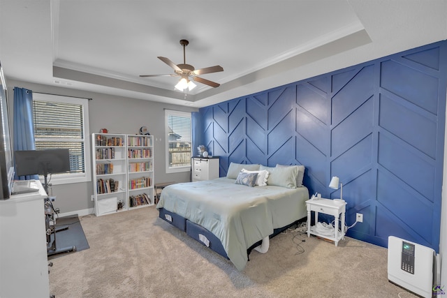 carpeted bedroom featuring a tray ceiling, heating unit, crown molding, and a decorative wall